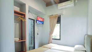 Una habitación de hotel con cama, armario, televisor y aire acondicionado.