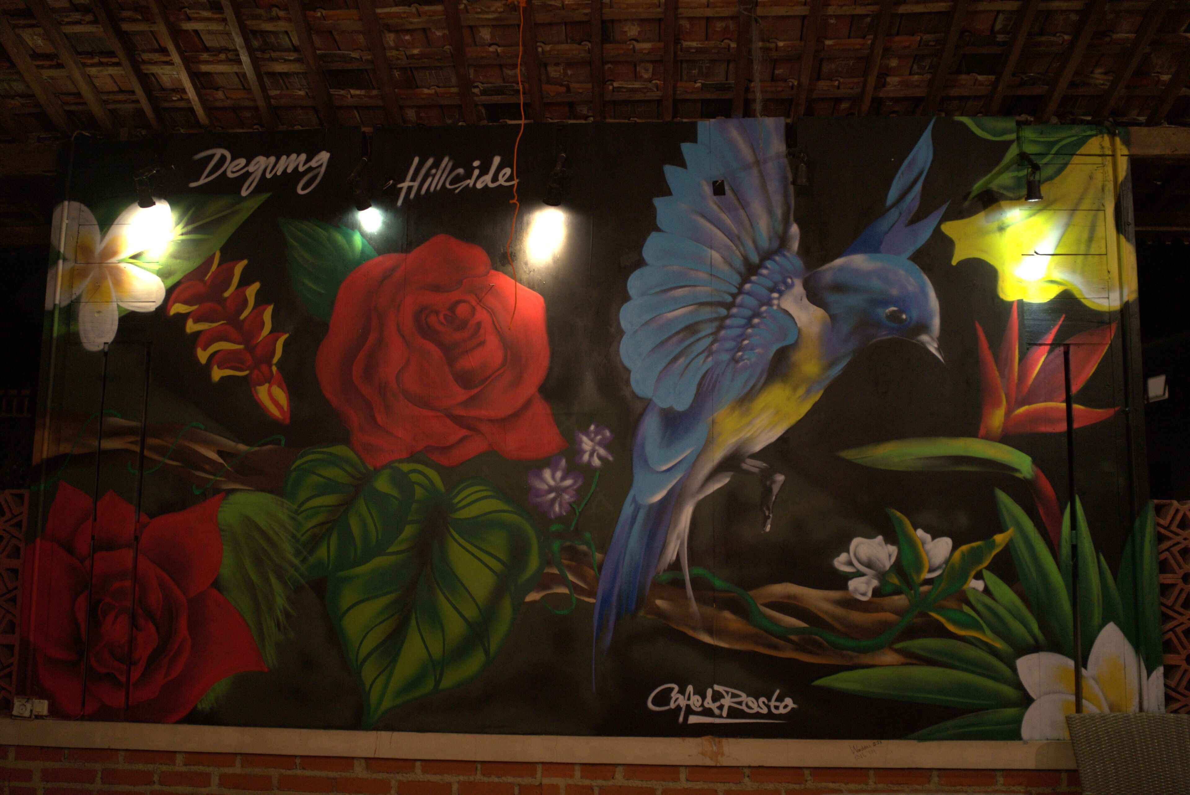 A mural with a bird, flowers, and text.