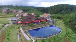 Zona residencial con piscina, varias casas y un paisaje verde exuberante.