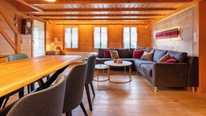 A cozy cabin interior with a wooden dining table, a sofa, and a small coffee table.