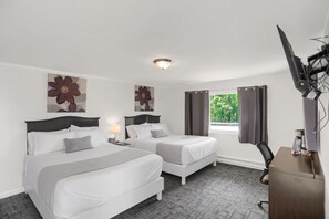 Une chambre d’hôtel avec deux lits, un bureau, une chaise et un téléviseur.