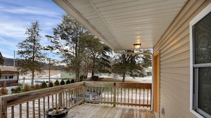 A wooden deck with a potted plant, overlooking a snowy landscape with trees and a building in the background. - Halifax Inn (Halifax)