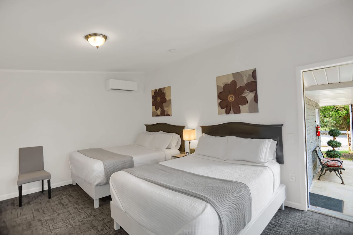 A hotel room with two beds, a chair, and artwork on the walls.