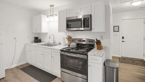 A modern kitchen with white cabinets, stainless steel appliances, and a granite countertop. - Halifax Inn (Halifax)