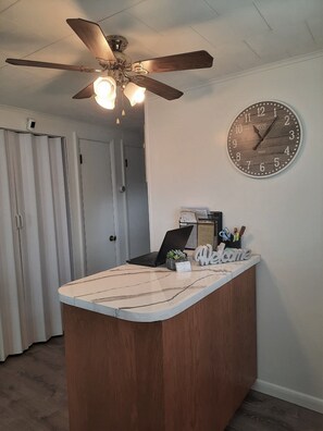 A reception desk with a clock, a laptop, and a welcome sign.