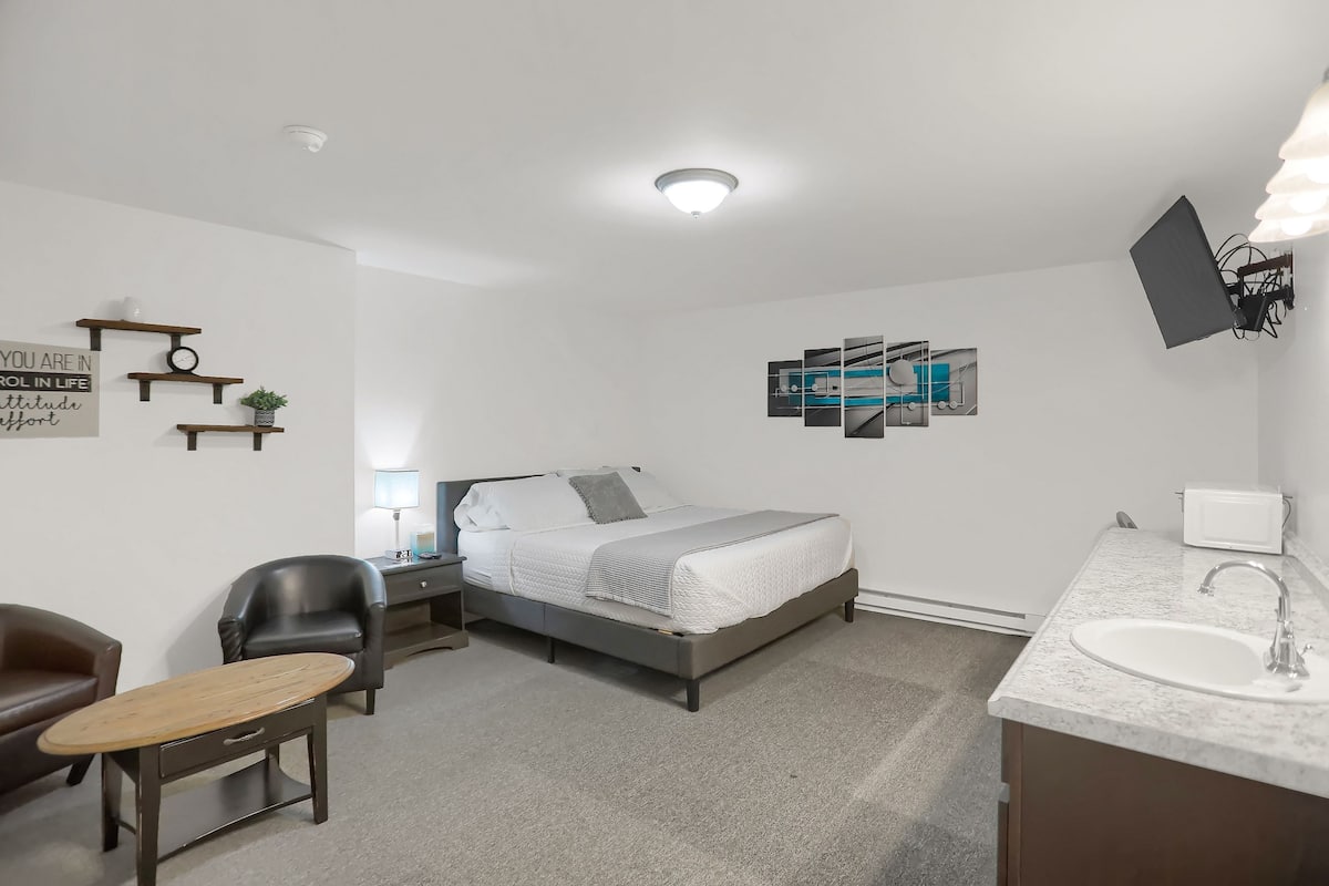 A modern bedroom with a bed, bedside table, chair, and a small desk.