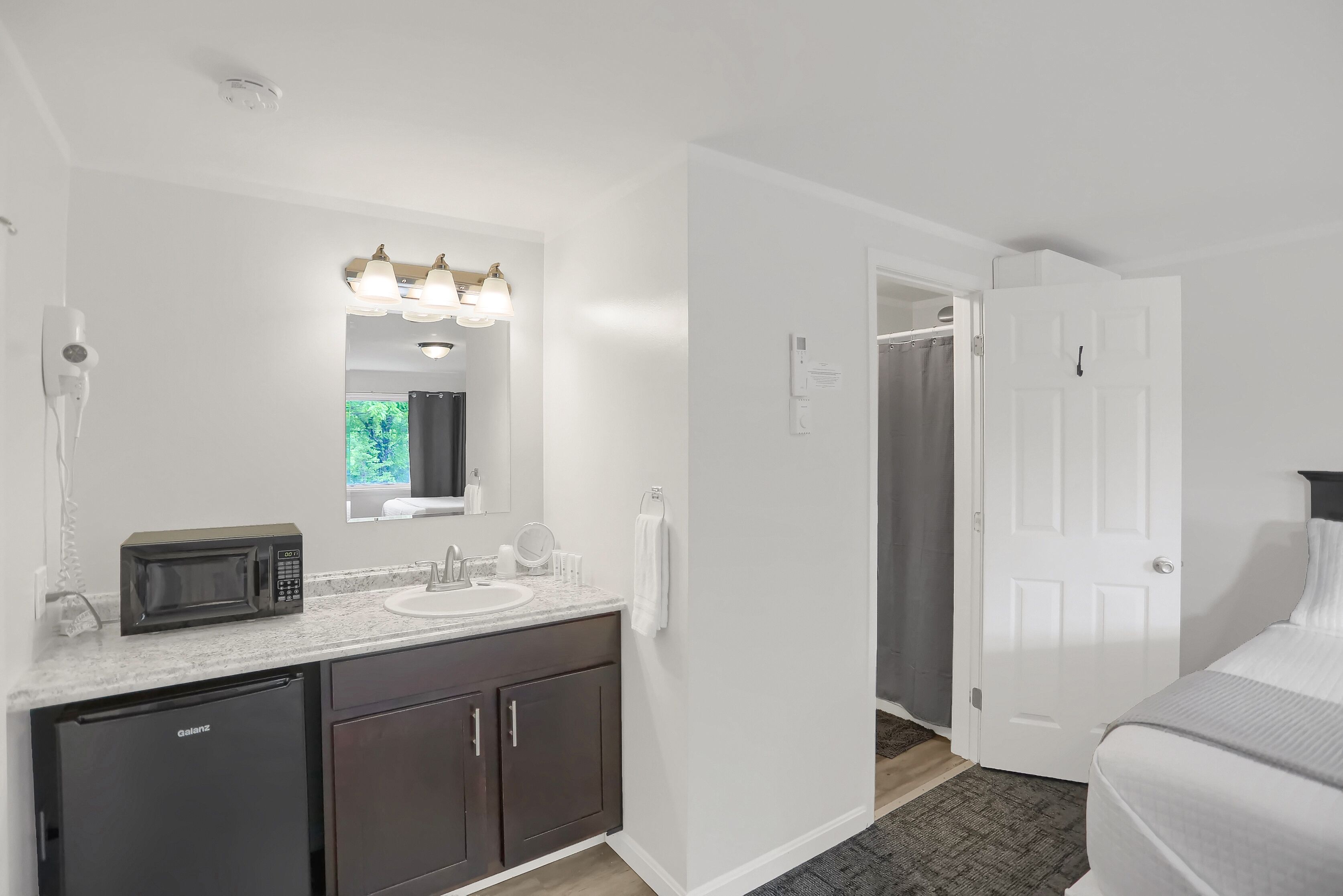 A modern bathroom with a sink, mirror, and a microwave.