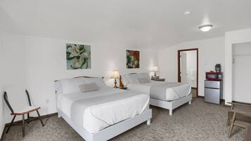 A hotel room with two beds, a desk, a chair, a microwave, and a refrigerator.