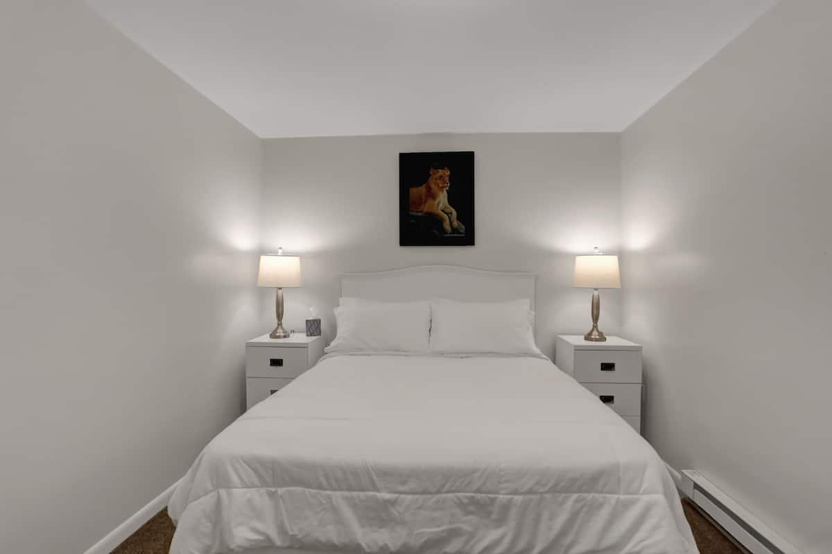 A bedroom with a large bed, two bedside tables, and a wall-mounted painting.
