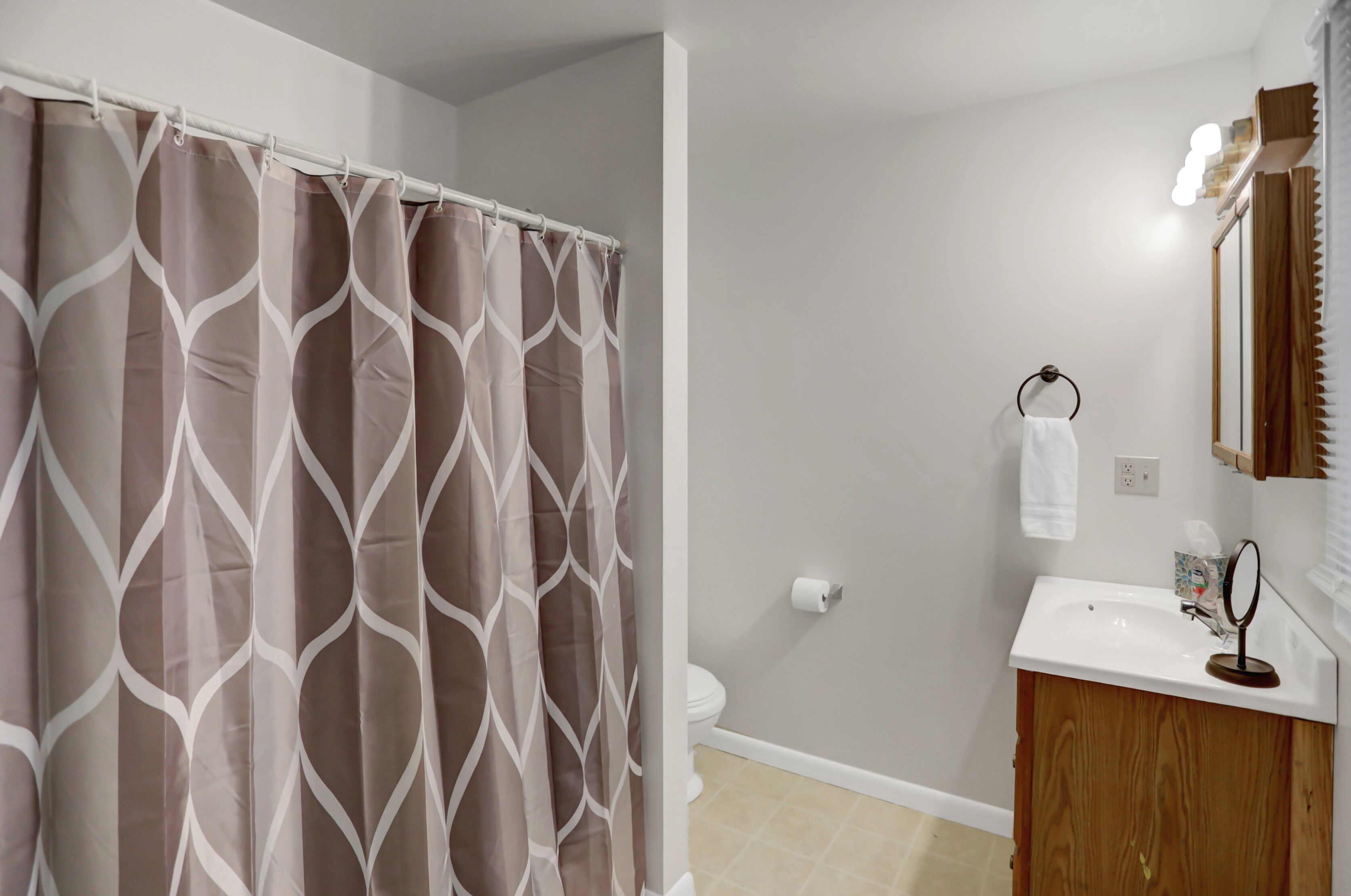 Une salle de bain équipée d’un rideau de douche, de toilettes, d’un lavabo et d’un miroir.