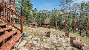 A wooden staircase leading to a deck with stone steps, surrounded by trees and a mountain in the background. - Heavenly Pines -- Ev #3361 5 Bedroom Home by RedAwning (Estes Park)