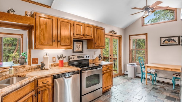 A kitchen with wooden cabinets, stainless steel appliances, a stone tile floor, and a ceiling fan. - Heavenly Pines -- Ev #3361 5 Bedroom Home by RedAwning (Estes Park)