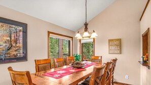 A dining room with a wooden table, six chairs, a chandelier, and a painting on the wall. - Heavenly Pines -- Ev #3361 5 Bedroom Home by RedAwning (Estes Park)