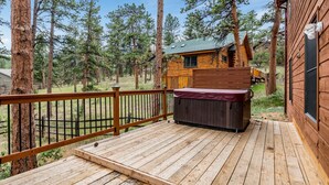 A wooden cabin with a deck, surrounded by tall pine trees. - Heavenly Pines -- Ev #3361 5 Bedroom Home by RedAwning (Estes Park)