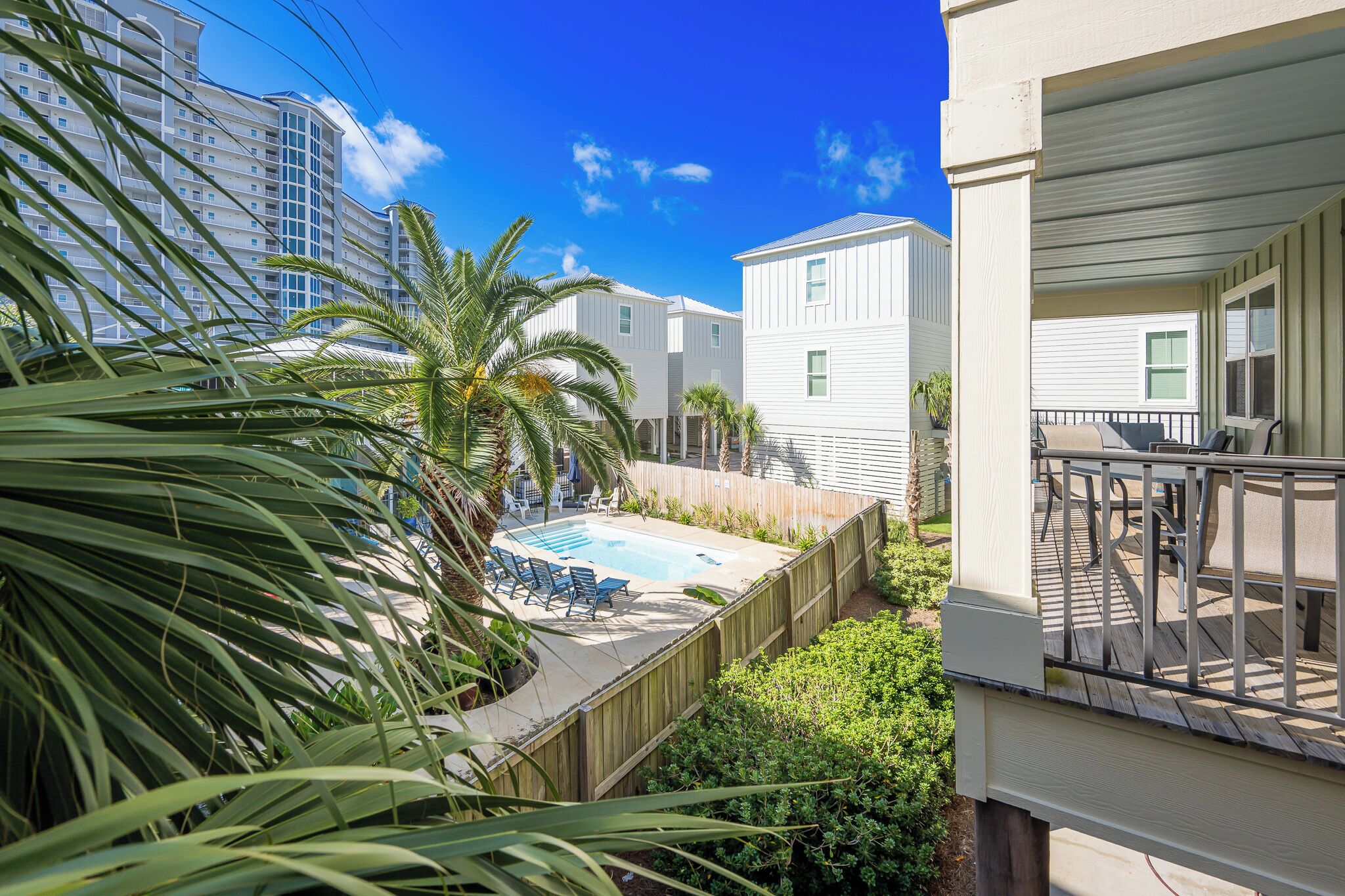 A residential area with a swimming pool, wooden deck, and a view of a tall building in the background.