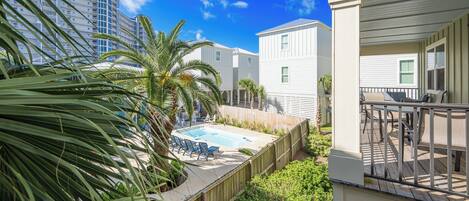A residential area with a swimming pool, wooden deck, and a view of a tall building in the background.