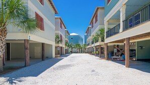 Une rue côtière bordée d’immeubles à plusieurs étages, de palmiers et d’un ciel d’un bleu limpide.