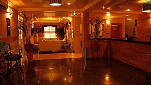 A hotel lobby with a polished marble floor, a reception desk, and several potted plants. - The Carlton Gate Hotel (Ibadan)