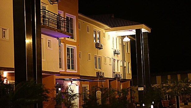 A multi-story hotel with balconies, a well-lit entrance, and outdoor seating areas. - The Carlton Gate Hotel (Ibadan)
