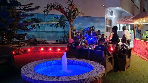 Área externa com fonte, assentos e um bar decorado com bambu.