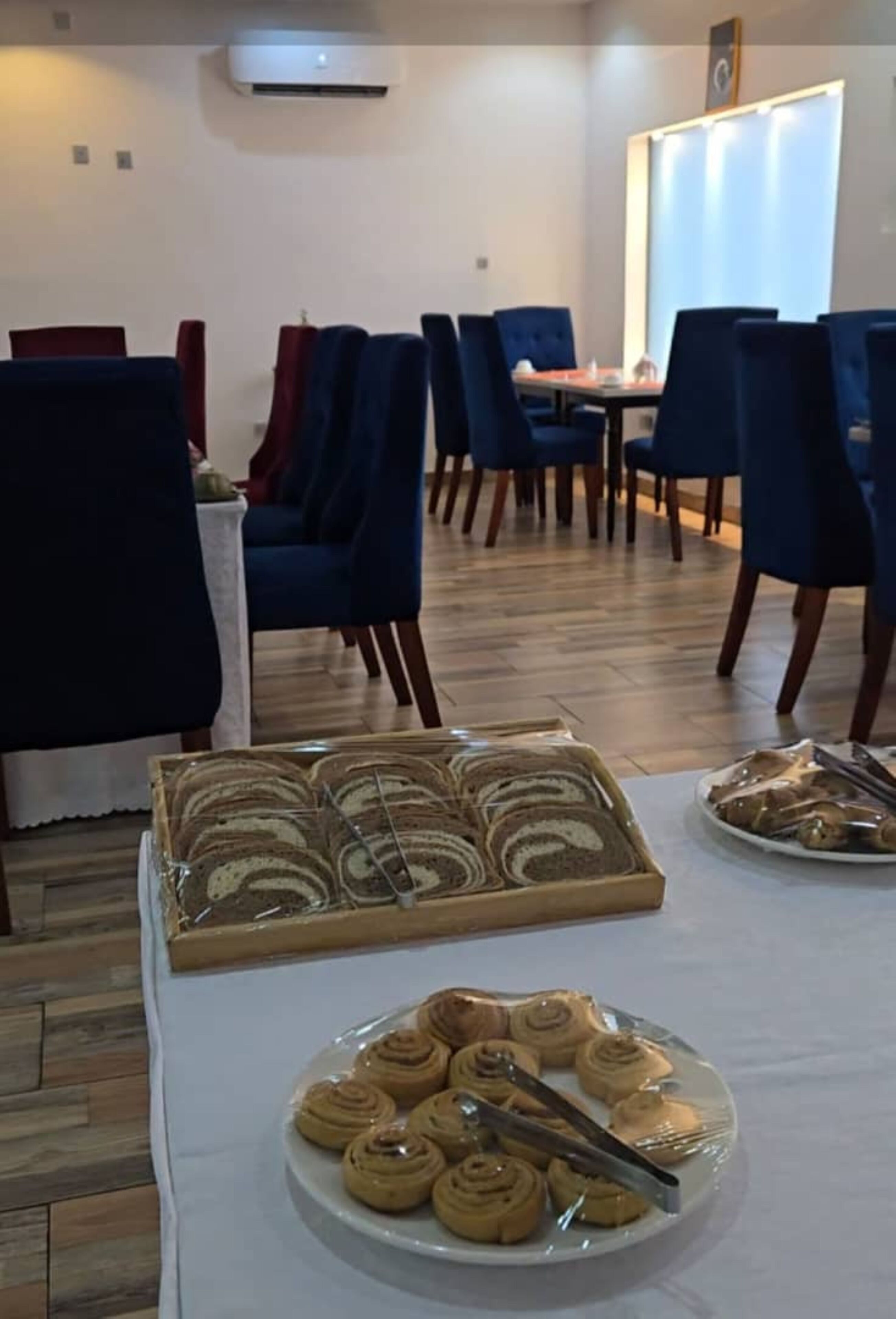 Un comedor con mesas, sillas y una selección de pasteles.