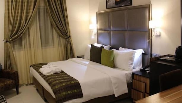 A hotel room with a bed, a desk, a chair, and a television. - Class Suites Signature (Lagos)
