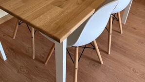 Ein Holztisch mit einer weißen Schüssel, umgeben von weißen Stühlen.