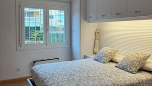 Ein Schlafzimmer mit einem Bett, einem Deckenventilator, einem Fenster und grauen Schränken.