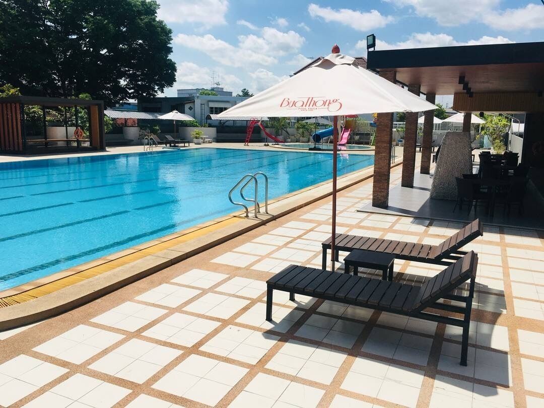 A swimming pool with lounge chairs and a covered area.