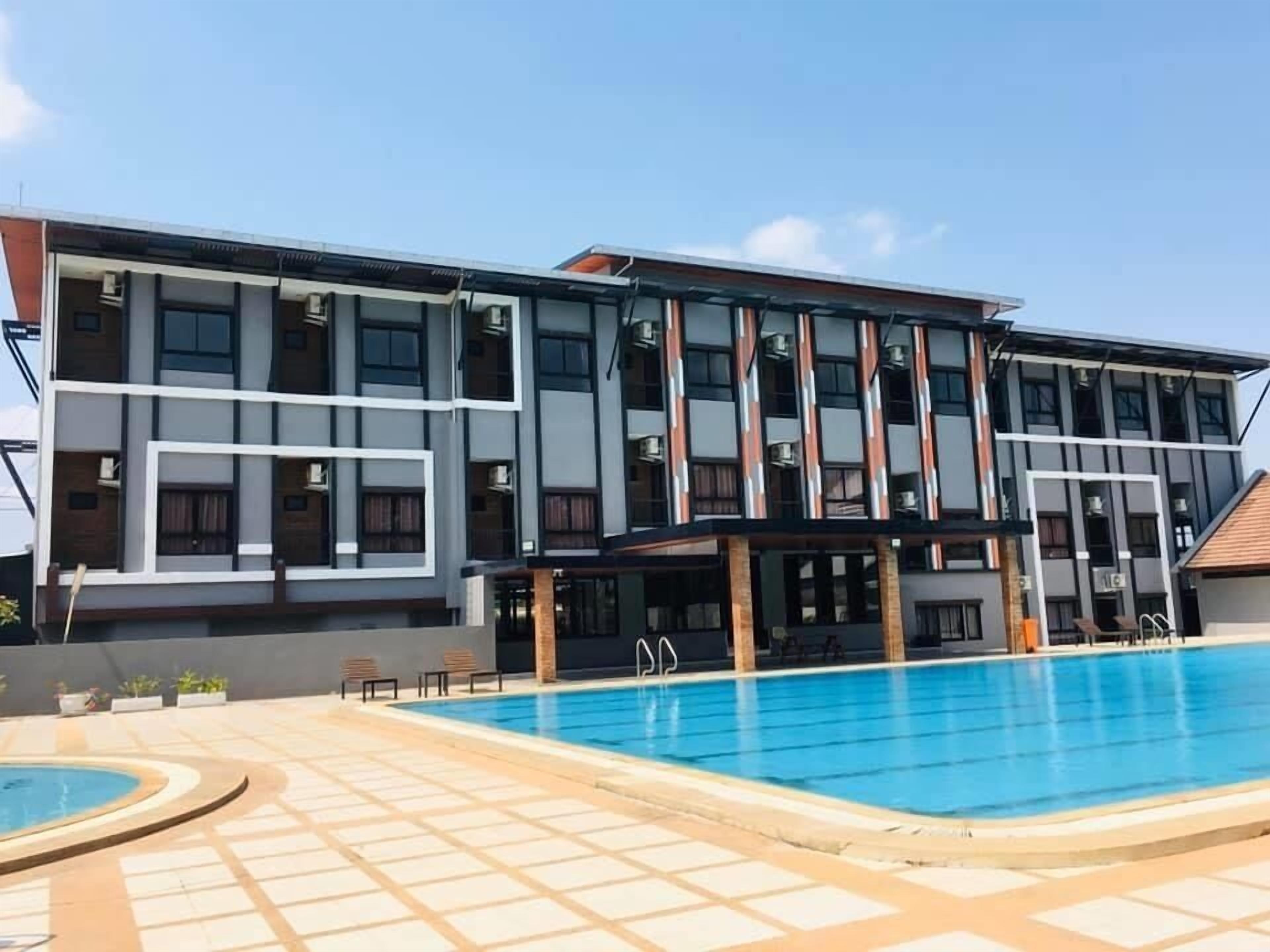 A modern hotel with a swimming pool, multiple balconies, and a covered outdoor seating area.