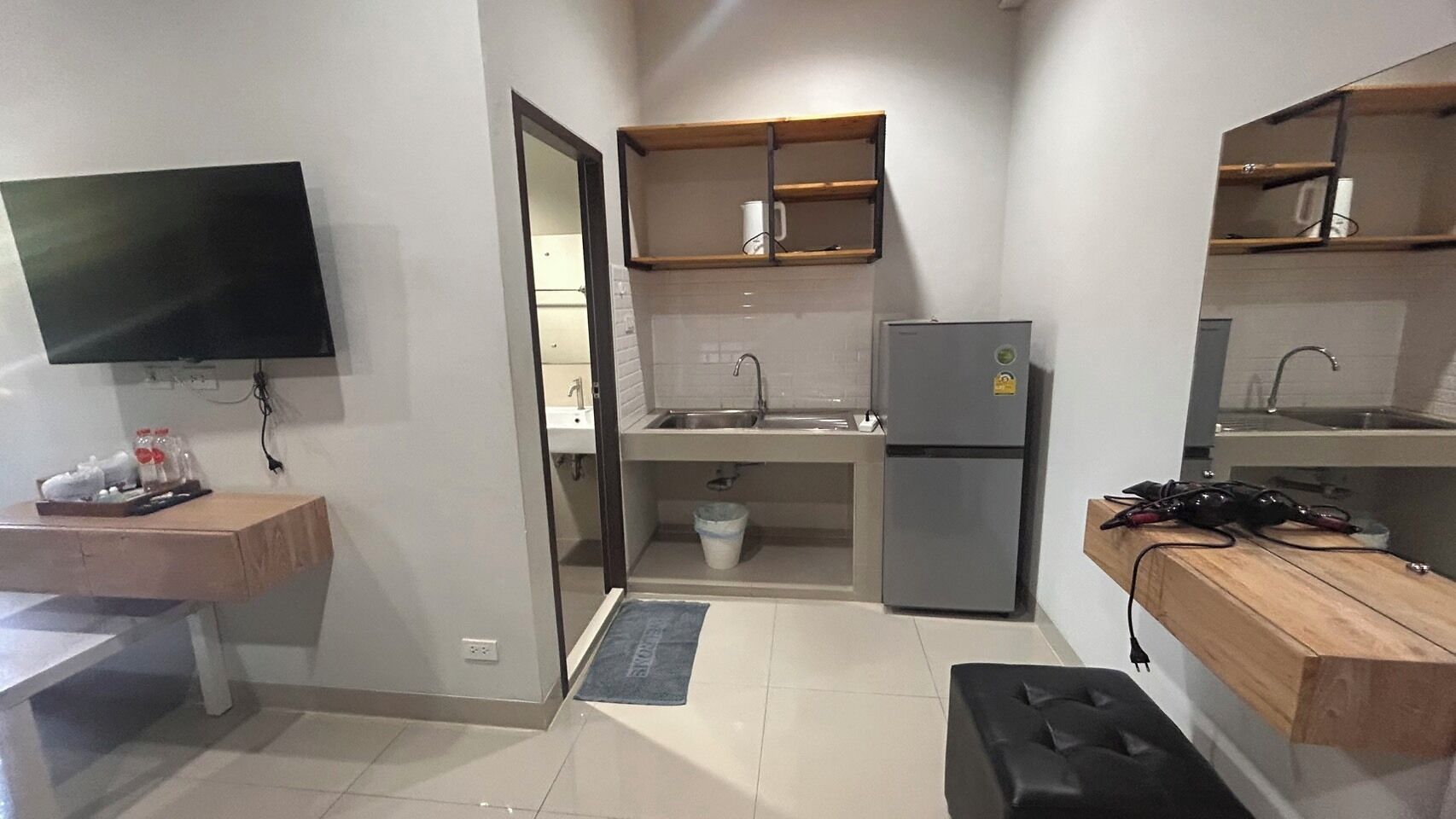 Una cocina compacta con un lavamanos integrado, un refrigerador y una encimera de madera.