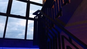 Una escalera con barandilla negra y un ventanal con vista al cielo.