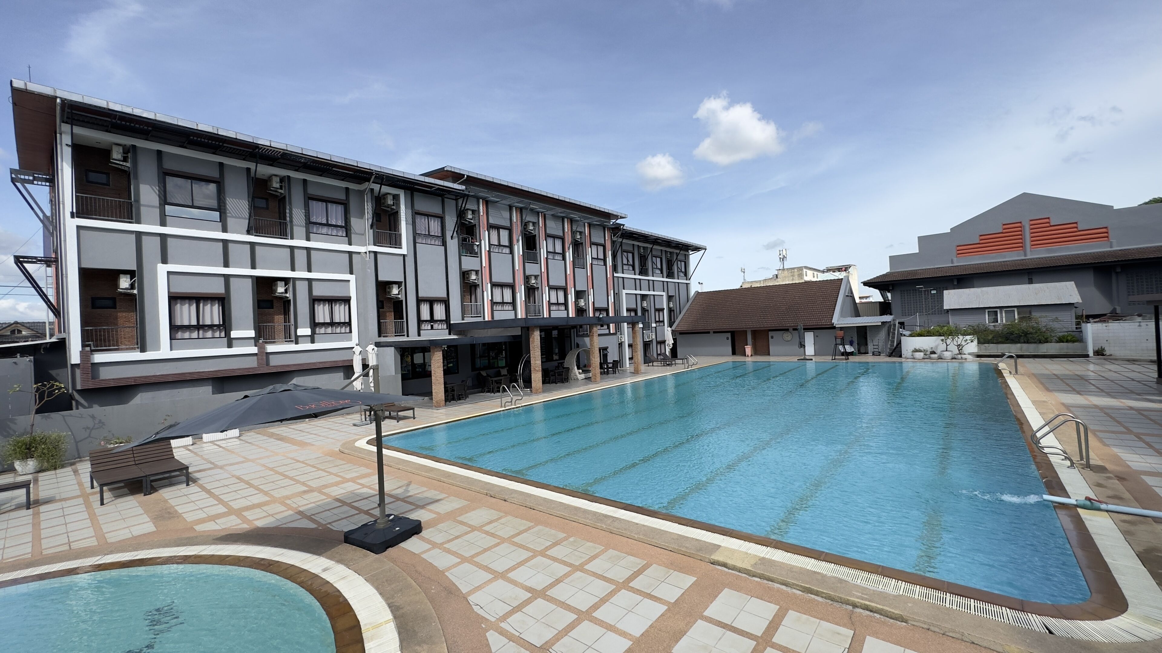 Un hôtel moderne doté d’une piscine, d’un espace extérieur aménagé et d’une zone couverte.