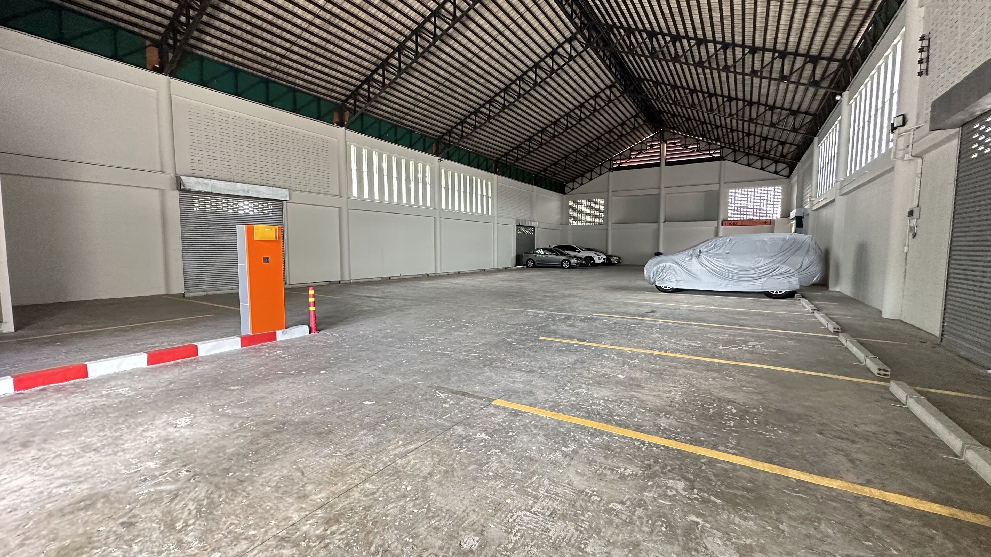 A large indoor parking area with concrete floors and metal roofing.