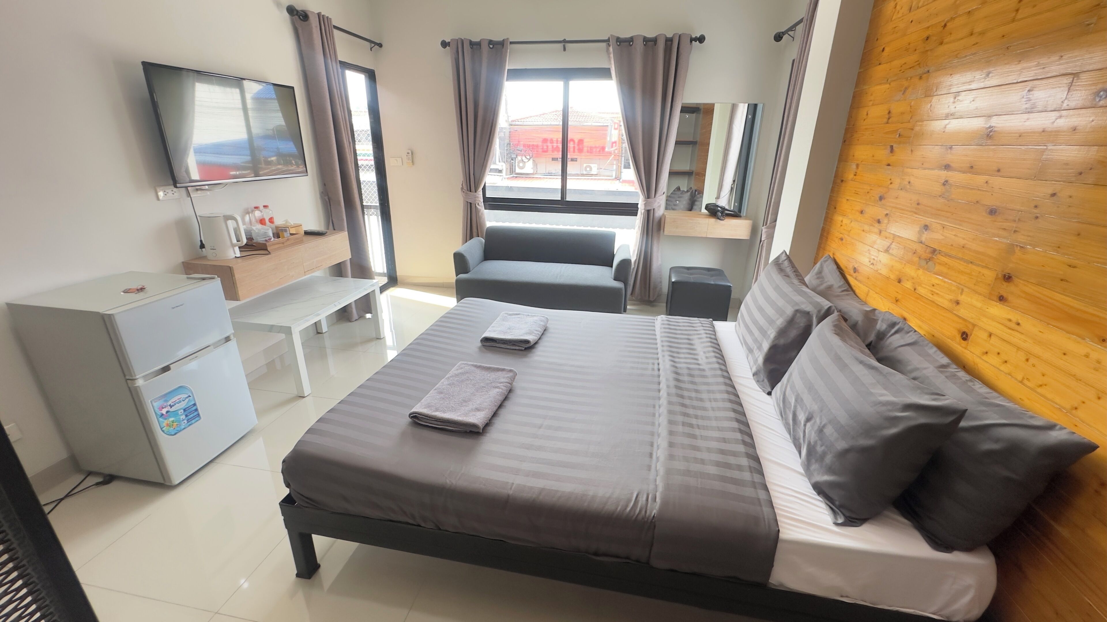 A hotel room with a bed, a desk, a chair, a TV, and a window with curtains.