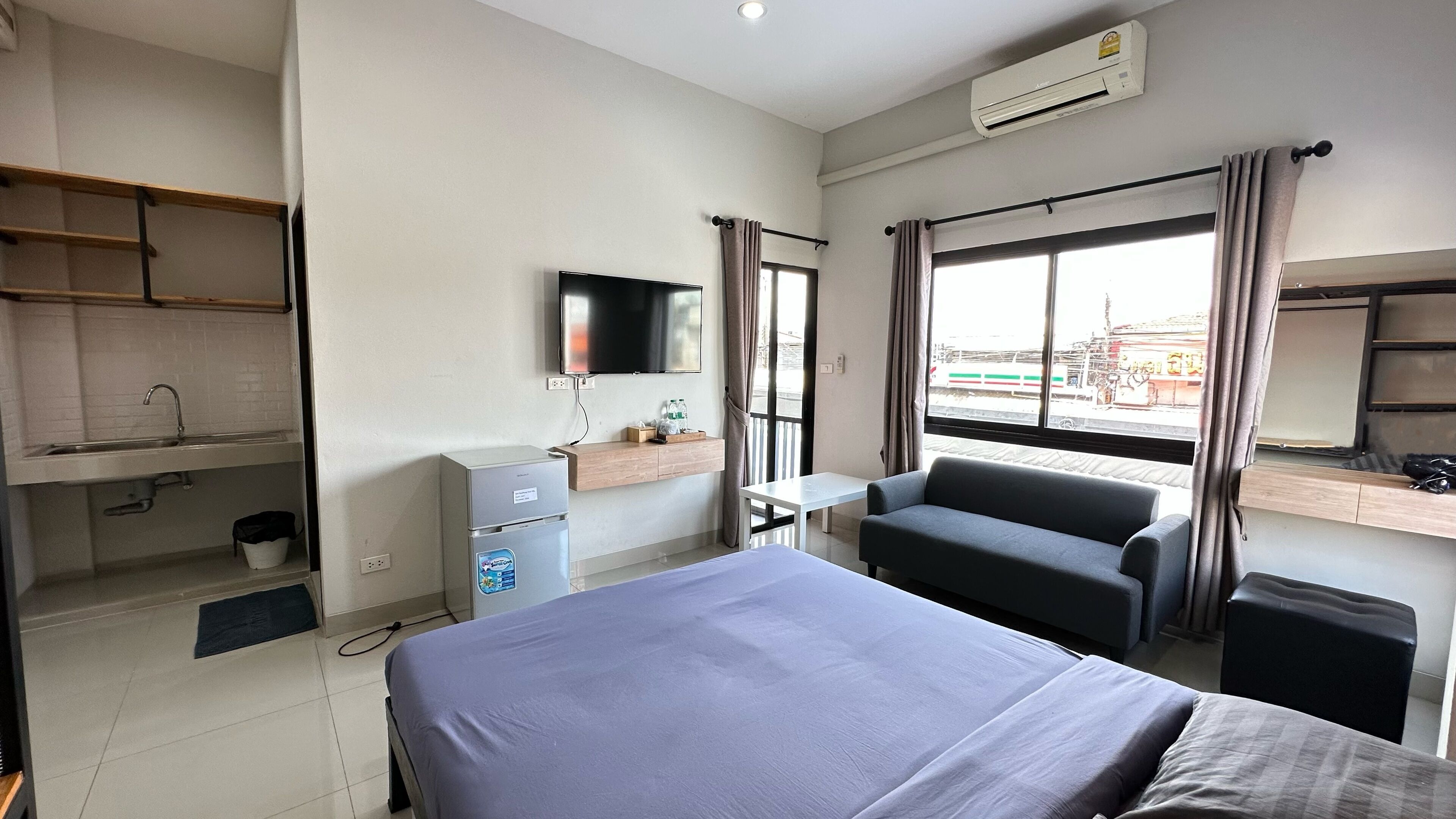 Ein Hotelzimmer mit Bett, Schreibtisch, Stuhl, Fernseher, Minikühlschrank, einem Fenster mit Außenblick und einem Ablagefach für Pflegeprodukte.