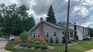 A two-story house with a brick chimney, a front porch, and a well-maintained lawn. - Rye Beach Retreat · Cozy Cottage on Rye Beach with Lake Erie view! (Huron)
