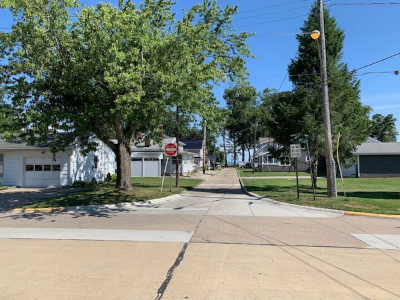 A residential street with houses, a stop sign, and a clear sky.