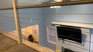 A room with a fireplace, a ceiling fan, and a window with blinds. - Rye Beach Retreat · Cozy Cottage on Rye Beach with Lake Erie view! (Huron)