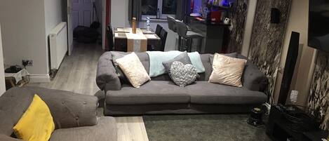A living room with a grey sofa, a brown sofa, a wooden coffee table, and a TV stand with a flat-screen TV.