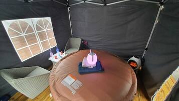 Una carpa con una mesa redonda, una silla y un ventanal con un diseño geométrico.