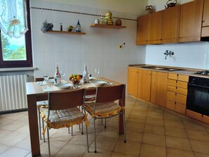 Una cocina con armarios de madera, una mesa de comedor con platos, vasos y un frutero.