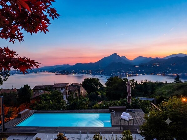 A swimming pool with a view of mountains and a lake at dusk.