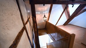 A wooden staircase with a hanging light fixture in a rustic room with exposed beams and a sloped ceiling. - RefuKium "Alte Gerberei" in der Innenstadt  (Weißenburg in Bayern)