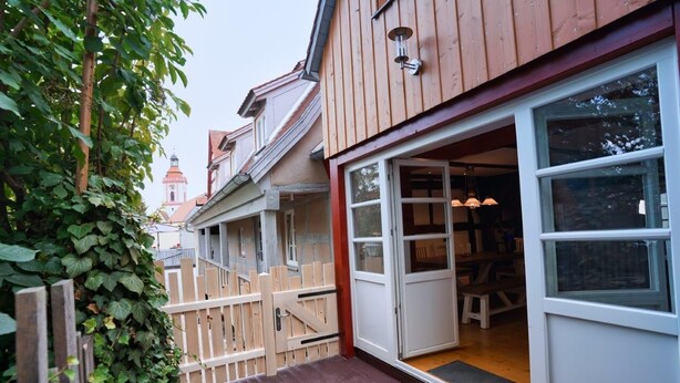 A wooden building with a large open door and a wooden fence. - RefuKium "Alte Gerberei" in der Innenstadt  (Weißenburg in Bayern)