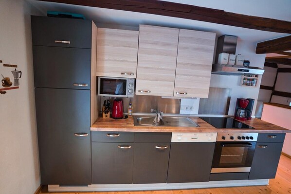 Una cocina moderna con armarios grises, microondas, cafetera y lavavajillas.