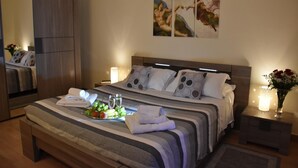 A modern hotel room with a large bed, a bedside table with a vase of flowers, and a nightstand with a lamp. - VILLA FENICE (Sicilia)