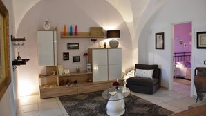 A living room with a sofa, a glass coffee table, a cabinet, and a bookshelf. - VILLA FENICE (Sicilia)