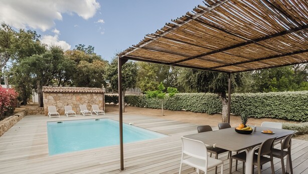 Une terrasse en bois avec une piscine, un espace salon extérieur et une pergola.