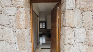Un couloir aux murs de pierre mène à une pièce dotée d’une porte en bois.
